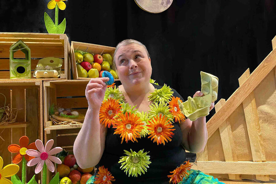 J'me cache ! La comédienne de conteuse avec ses pommes, ses œufs et ses fleurs entourées sont des corps tout en bois.