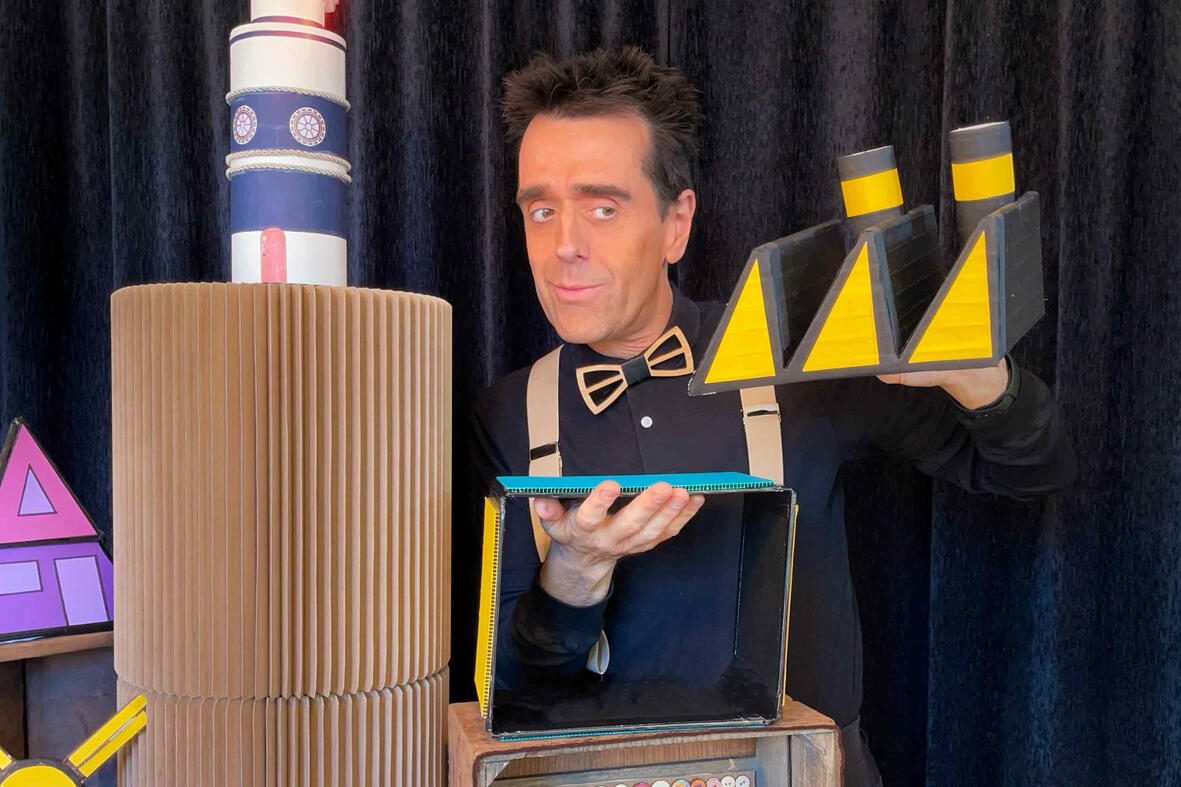 Monsieur Fred en spectacle, entouré de l’univers de Risque-Tout avec le village, la maison et l’île, offrant des surprises aux enfants.