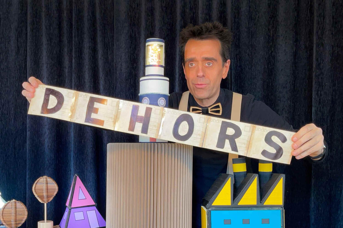 Scène du spectacle “Risque-Tout” : Monsieur Fred, le personnage principal et la petite maison sur l’île, devant un jeune public émerveillé.